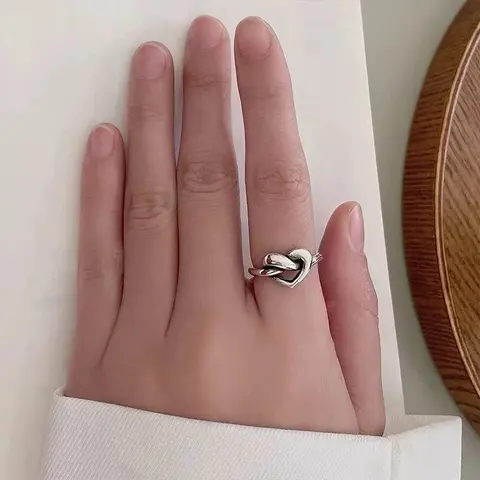Silver heart-knot ring worn on a hand