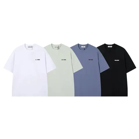 Four plain short-sleeve tees in white, sage, slate blue and black with a small chest label